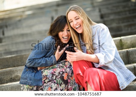 Similar – Two women laughing looking at their smart phone