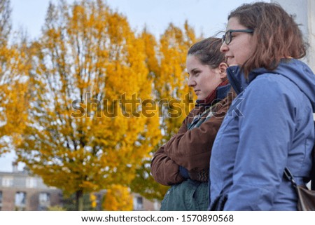 happy twin sisters stand on a bridge and look up