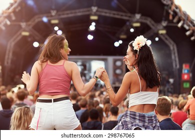 Two girls on shoulders in the crowd at a music festival