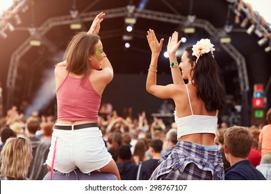 Two girls on shoulders in the crowd at a music festival - Powered by Shutterstock