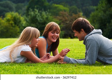 Two girls and one guy flirting in a meadow