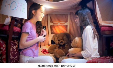 Two Girls In Pajamas Telling Stories At Dark Night