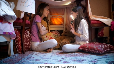 Two Girls In Pajams Sitting In Tepee Tent And Telling Scary Stories