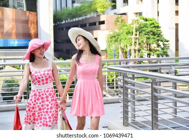 Two Girls In A Pink Dress And A Pink Hat Leave Shopping At A Shopping Mall With A Product Coming Together. During Summer Holidays