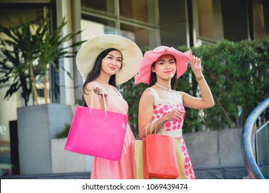 Two Girls In A Pink Dress And A Pink Hat Leave Shopping At A Shopping Mall With A Product Coming Together. During Summer Holidays