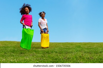 Two girls play gunny sack race jumping downhill - Powered by Shutterstock