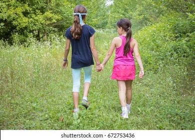 Two girls playing at a natural reserve with one of them being blindfolded