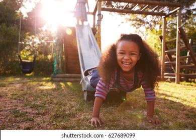 Two Girls Playing Outdoors At Home On Garden Slide