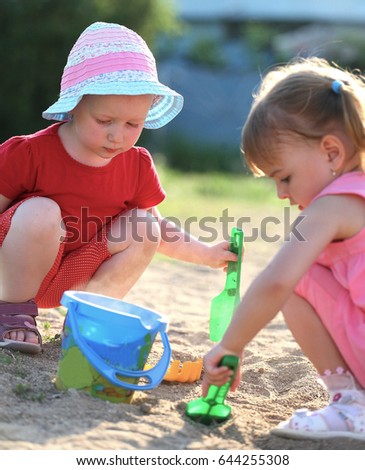 Similar – children playing in the sand, having a conversation over sand toys