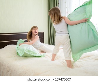 Two Girls Playing With Pillows In Bedroom