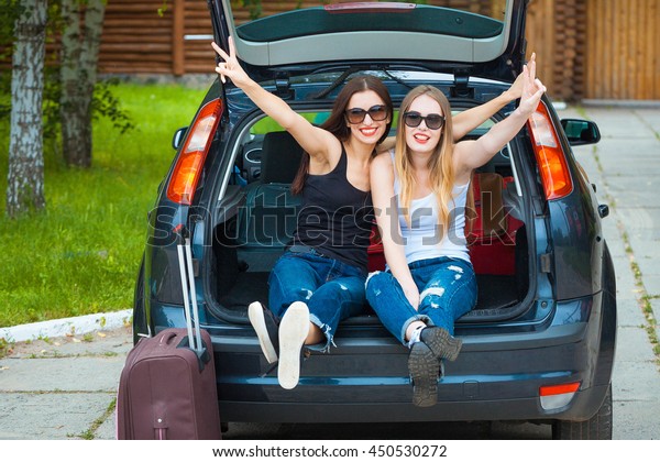 Two girls posing in car. Resting in the\
country. taking a trip somewhere by\
car