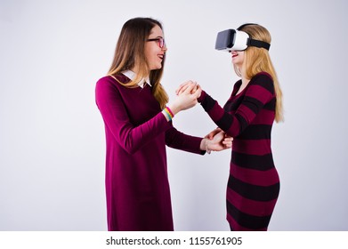 Two Girls In Purple Dresses Trying Out Virtual Reality Glasses In The Studio.