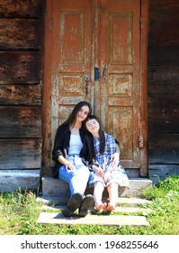 Two Girls Are Sitting On The Porch Of An Old Wooden House