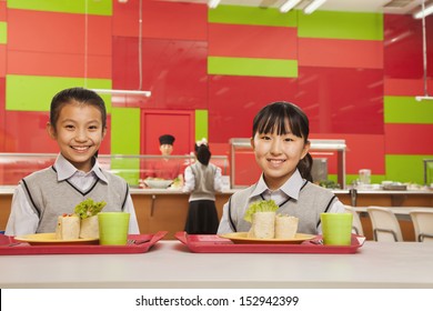 Two Girls Sitting In School Cafeteria