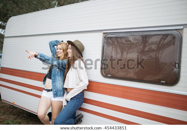 Two girls smiling in a\
camping van.