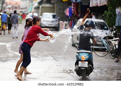 Two girls splash the buckets of water to a man who ride motorcycle in the Songkran festival. Songkran festival, aka water war, is held in Thailand during 13-15 April every year. 14/04/2017 Maesot Tak