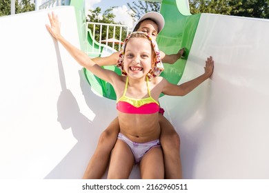 Two Girls Splash In An Outdoors Swimming Pool In Summer. Happy Children, Sister Playing, Enjoying Sunny Weather In Public Pool