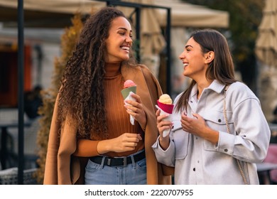 Two girls are strolling, talking and eating cone ice cream, and having much fun in the town. - Powered by Shutterstock