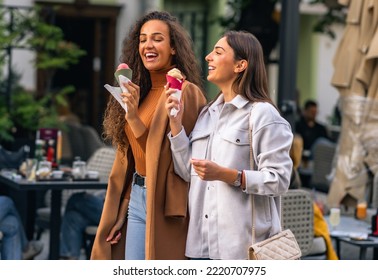 Two girls are strolling, talking and eating cone ice cream, and having much fun in the town. - Powered by Shutterstock