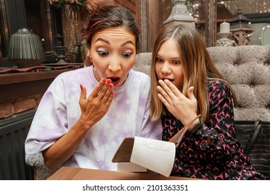 Two Girls Are Surprised And Shocked By The Final Bill For Dinner At The Restaurant. The Concept Of Price Increases And Currency Inflation. Financial Awareness And Security