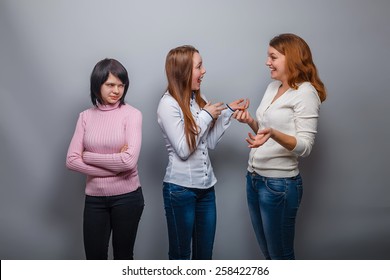 two girls talking blonde European appearance and ignore the third girlfriend on a gray background, resentment, sadness - Shutterstock ID 258422786