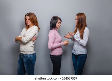 Two girls talking  blonde  European appearance and ignore the third girl on a gray background, resentment, sadness conflict friend - Shutterstock ID 264069557