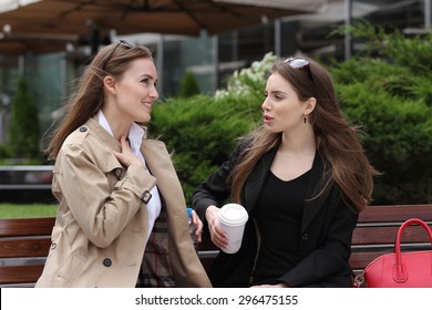 Two Girls Talking On The Bench In Front Of Business Center