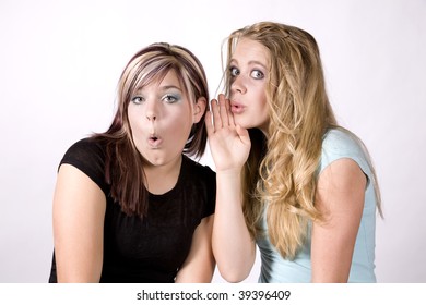Two girls telling a secret and looking surprised