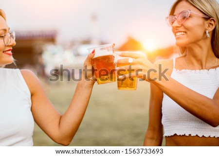Two girls toasting with beer at music festival