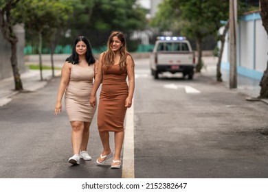 two girls walking down the middle of the avenue, expressing joy.