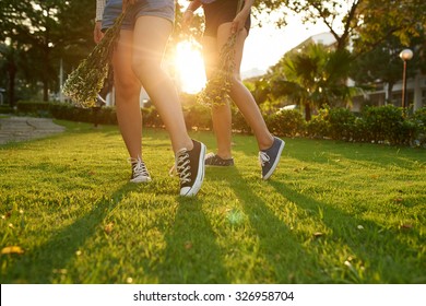 Two Girls Walking In Park With Flowers