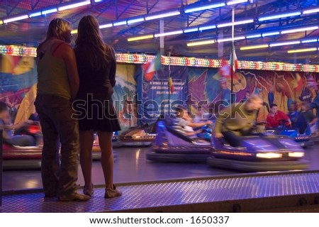 two girls watching bumper cars at the local fair