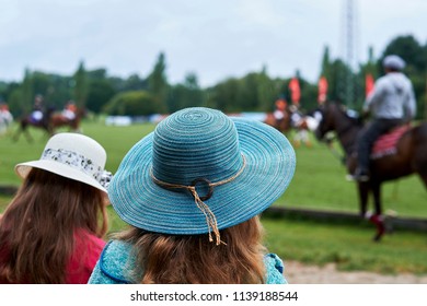 Two girls are watching a polo tournament
