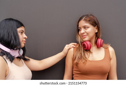 Two Girls Wearing Headphones, One Tapping The Other On The Shoulder