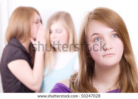 Two girls whispering, another girl in the depression