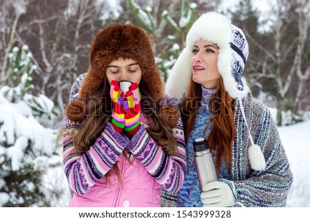 Two girls in the winter. winter picnic in the forest.  Family together on snowy day. Winter holiday. Mom and her daughter spending weekend. thermos of hot tea in winter.