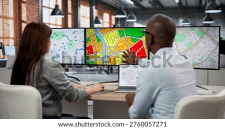 Two GIS Analysts In Office Using Computers To Review Urban Planning Maps. The Woman Checks Zoning Codes