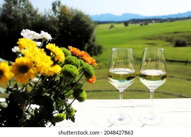 Two glaeses with whitewine on the balcony, beautiful bouquet with chrysanthemum on the left side, in the background alpine landscape, Allgäu, Bavaria