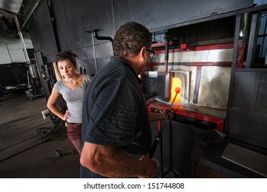 Two Glass Artists Putting Object In Hot Kiln