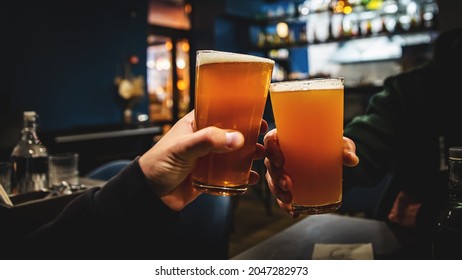 two glass of beer in hand. Beer glasses clinking in bar or pub - Powered by Shutterstock