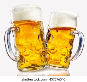 Two glass beer mugs full of golden lager with thick frothy heads over a reflective white background conceptual of the Oktoberfest - Powered by Shutterstock