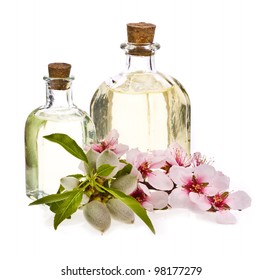 Zwei Glasflaschen mit Mandelöl und frischen Mandeln und Blumen einzeln auf weißem Hintergrund