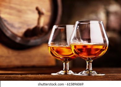 Two glass of Cognac and old oak barrel defocussed