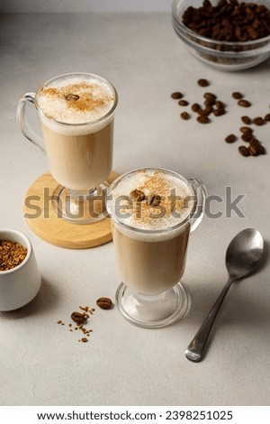 Two glass cups with coffee drink, latte with milk foam and cinnamon 