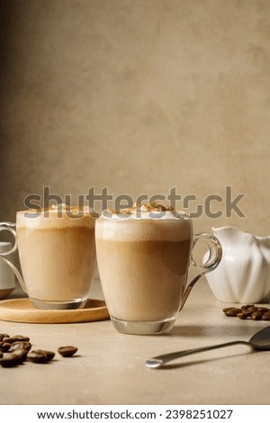 Two glass cups with coffee drink, latte with milk foam and cinnamon 