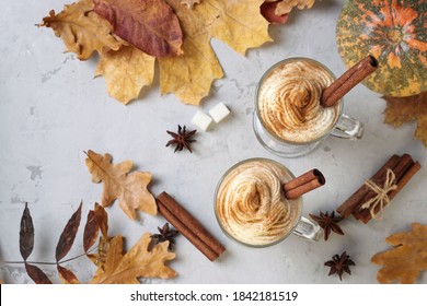 Two Glass Cups Pumpkin Latte With Spices On Grey Background With Pumpkins And Autumn Leaves. View From Above.