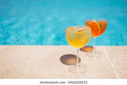 Two glass of delicious cocktails against poolside at resort hotel. Elegant goblet of ice drink with orange and limon slice on background of blue water outdoor at sunny day. Travel and relax concept. - Powered by Shutterstock