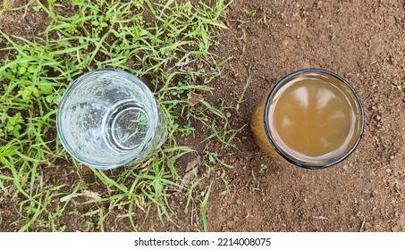 Two Glass Filled With Pure, Impure, Dirty, Clean, Unhygienic, Hygienic, Bad, Good, Purified, Contaminated Undrinkable And Drinkable Drinking Water On Ground Soil With Green Grass. Conceptual Photo.