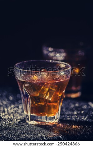 Two glass of iced cocktail on wet background. Vintage filter.