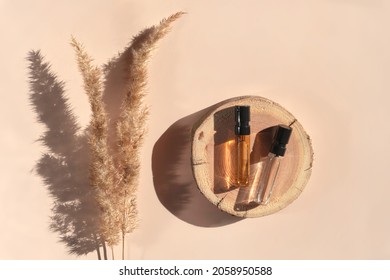 Two Glass Perfume Samples On A Wooden Tray Lying On A Beige Background With Pampas Grass. Luxury And Natural Cosmetics Presentation. Testers On A Woodcut In The Sunlight. Top View